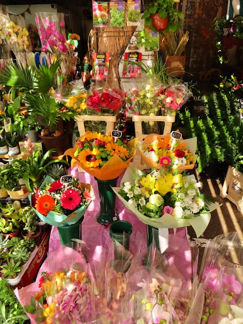A display of fresh floral bouquets arranged on tables inside a flower shop, featuring vibrant flowers such as red roses, pink gerbera daisies, and white chrysanthemums, wrapped in colorful tissue pape